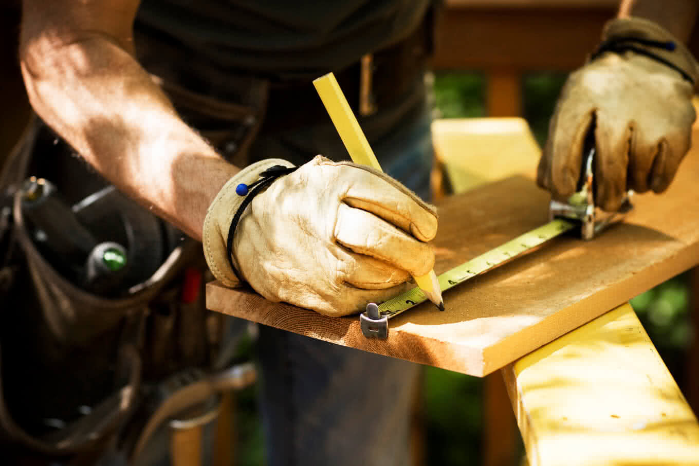 Carpenter measuring a wooden plank at a construction site