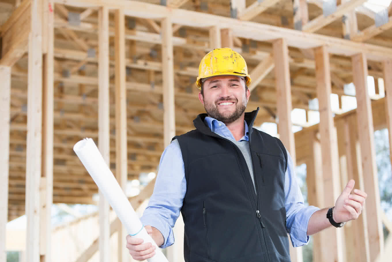 Worker with hardhat and plans at construction site